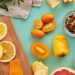 Colorful assortment of sliced fruits and vegetables on teal background, showcasing freshness.