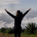 A woman with arms raised enjoying a scenic mountain view in Pinal de Amoles, Mexico.